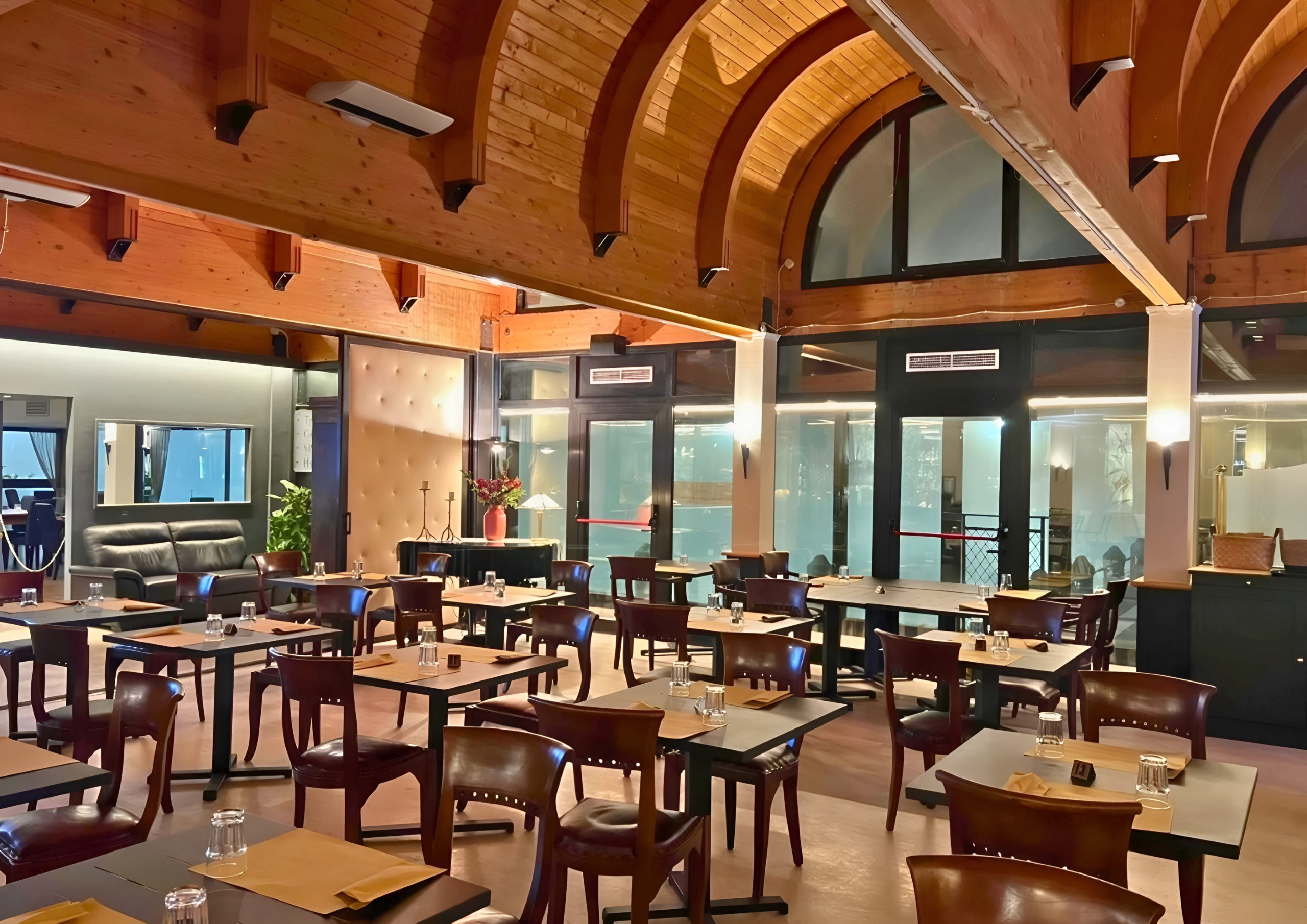 La sala del Bistrot 2.0, con il soffitto in legno ad archi e le vetrate sulla piscina